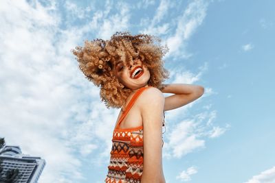 Side view of young woman standing against sky