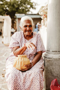 Portrait of smiling young woman sitting outdoors