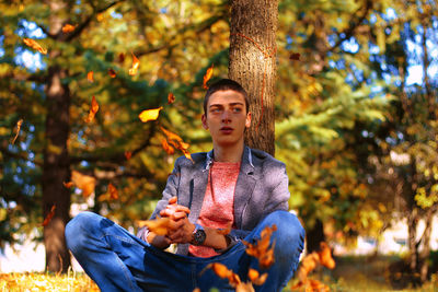 Thoughtful young man sitting at park during autumn