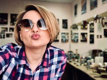 Portrait of smiling woman wearing sunglasses at home