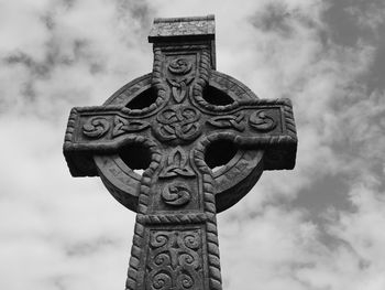 Low angle view of cross statue against cloudy sky