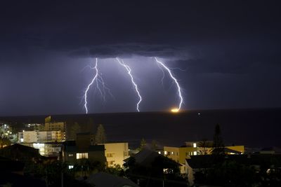 Lightning over illuminated buildings in city at night