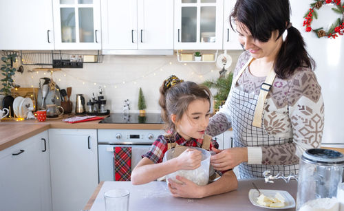 Mother and female friends preparing food in kitchen