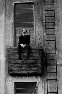 Man sitting in balcony of abandoned building