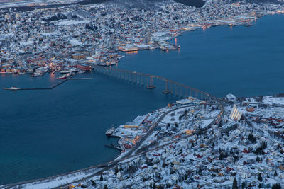 Aerial view of tromso bridge over fjord amidst towns against sky