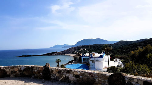 Scenic view of sea by mountains against sky