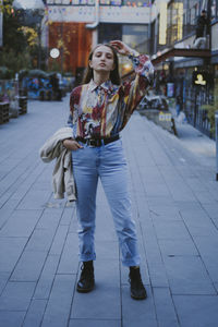 Full length of young woman standing on footpath