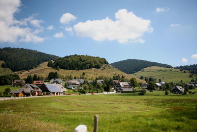 Houses on field by mountains against sky