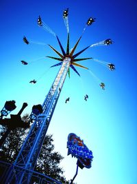 Low angle view of chain swing ride against clear blue sky