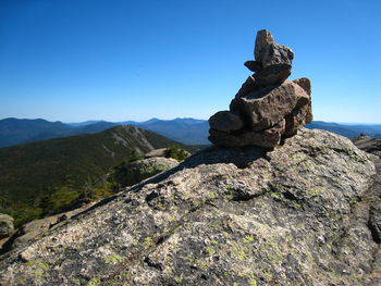 Stack of rocks on mountain against blue sky