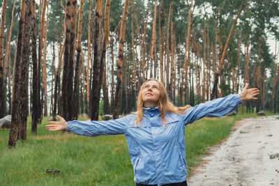 Portrait of woman standing against trees in forest