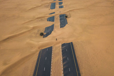 High angle view of silhouette person over road on sand in desert
