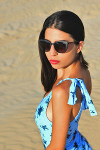 Portrait of young woman wearing sunglasses standing at beach