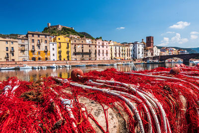 Red buildings by river against sky in city