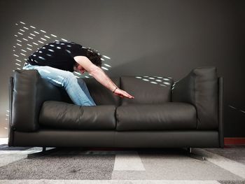 Side view of man sitting on sofa at home
