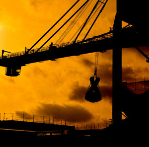 Low angle view of silhouette crane against sky