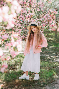 Portrait of young woman standing by flowering plants