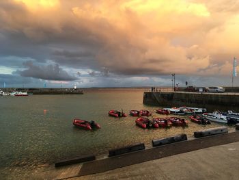 Boats moored at harbor against sky during sunset