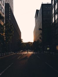 Road amidst buildings in city against clear sky