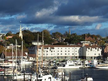 Sailboats moored in harbor against buildings in city