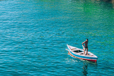 High angle view of man standing in rowboat on sea