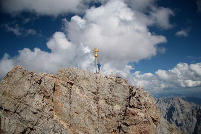 Low angle view of man standing by built structure on rock against sky