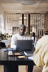 Businessman working on laptop while sitting at desk in coworking office