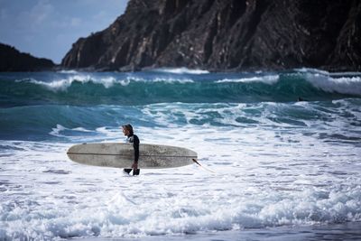 Man surfing in sea against sky