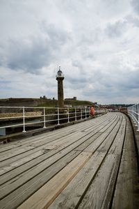 View of empty pier against cloudy sky