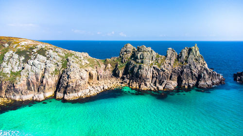 Panoramic shot of rocks and cliffs by sea against sky