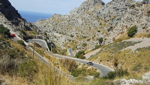 Scenic view of road by mountains against sky