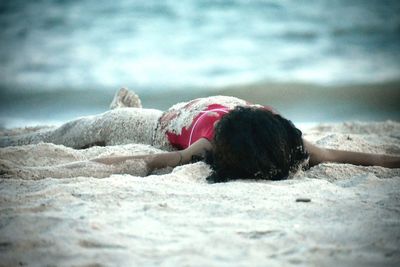 Carefree teenage girl lying on sand at beach