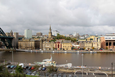 Buildings by river against sky in city