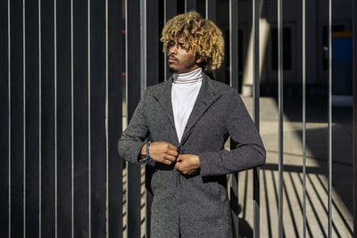 Portrait of young man standing against wall