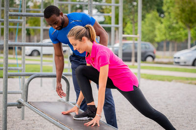 Fitness instructor guiding woman in exercise at park