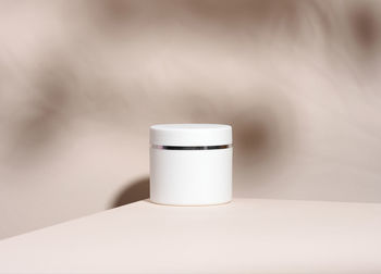 White jar for cosmetics on a beige table. packaging for cream, gel, serum, advertising and product 