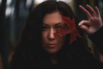 Close-up portrait of a beautiful young woman with leave against eye 