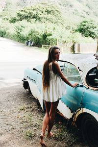 Young woman standing by car on tree