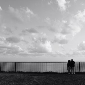 Rear view of couple standing by sea against sky