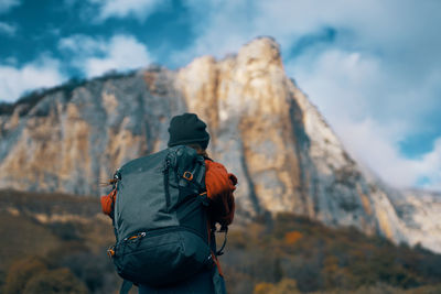 Rear view of man standing on mountain against sky