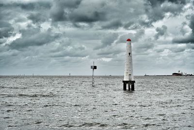 Lighthouse by sea against sky