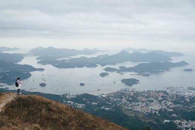 Side view of young woman on mountain against cloudy sky