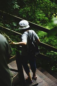 Rear view of man standing by railing against trees