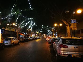 Cars on illuminated street in city at night