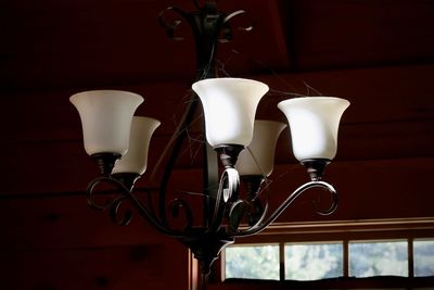 Low angle view of illuminated light bulb against white wall