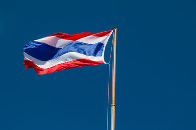 Low angle view of thai flag waving against clear blue sky