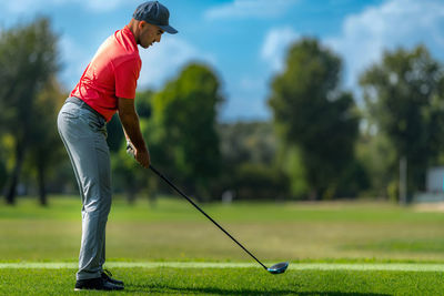 Golfer preparing to hit a golf ball, beautiful day on a golf course