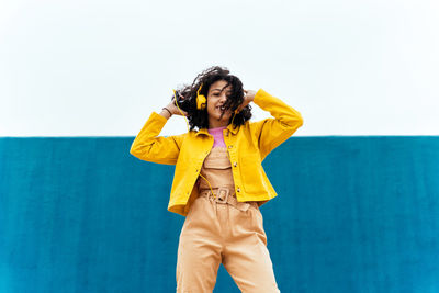 Young woman standing against blue sky