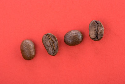 High angle view of roasted coffee beans on red background