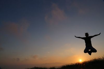 Low angle view of silhouette man jumping against sky during sunset